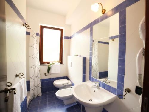 een blauwe en witte badkamer met 2 toiletten en een wastafel bij Le Oreadi in Francavilla di Sicilia