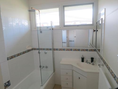 baño blanco con ducha y lavamanos en Edge Hill Clean & Green Cairns, 7 Minutes from the Airport, 7 Minutes to Cairns CBD & Reef Fleet Terminal en Cairns