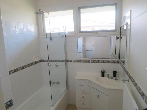 a white bathroom with a shower and a sink at Edge Hill Clean & Green Cairns, 7 Minutes from the Airport, 7 Minutes to Cairns CBD & Reef Fleet Terminal in Cairns