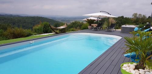 une grande piscine bleue sur une terrasse avec un parasol dans l'établissement Villa d'escane, à Escanecrabe