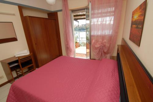 a bedroom with a pink bed and a window at Hotel Baia Del Sorriso in Castiglioncello