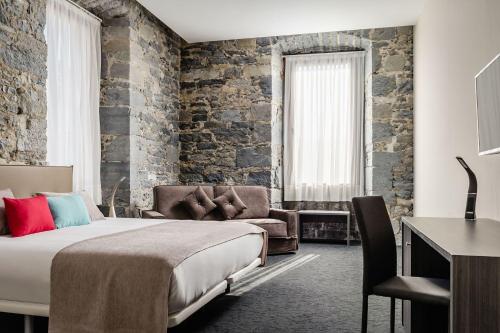 a bedroom with a bed and a chair and a desk at Hotel Balneario Orduña Plaza in Orduña
