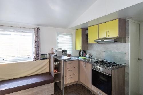 a kitchen with yellow cabinets and a stove top oven at Camping Les Maraises in Saint-Martin-de-Ré