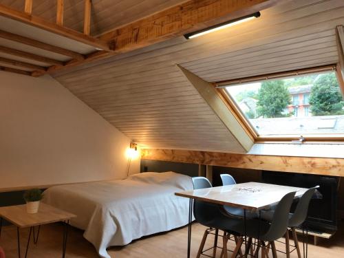Schlafzimmer mit einem Bett, einem Tisch und einem Fenster in der Unterkunft Joli studio 4P entre télécabine et Commerces in Cauterets