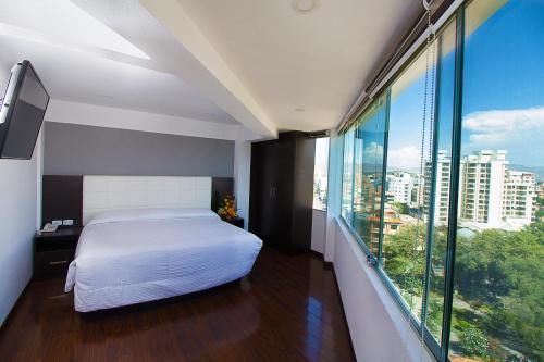 a bedroom with a bed and a large window at Apart Hotel Regina in Cochabamba