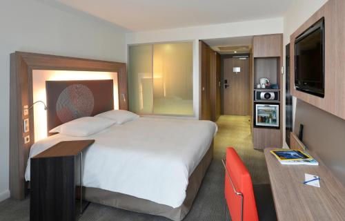 a hotel room with a large bed and a table at Novotel Avignon Centre in Avignon