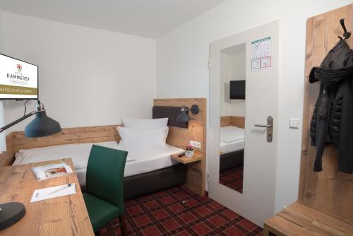 a small room with a bed and a desk and a table at Hotel Kammerer in Sankt Georgen im Schwarzwald