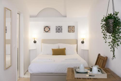 a white bedroom with a bed and a table at Casa Candeias in Évora