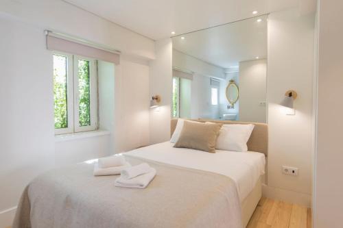 リスボンにあるLovelyStay - Principe Real: modern and comfort!の白いベッドルーム(ベッドに白いタオル2枚付)