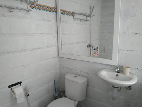 a white bathroom with a toilet and a sink at Tanjong Tinggi Cottage in Sijuk