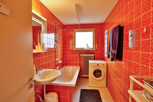 a red tiled bathroom with a sink and a washing machine at Zimmervermietung Familie Kolb in Oberessendorf