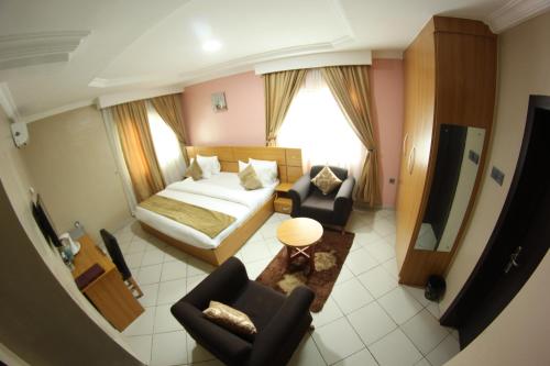 a hotel room with a bed and two chairs at Celia's Suites in Abeokuta