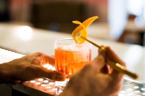 a person holding a drink with an orange garnishment at MYR Marqués House in Valencia
