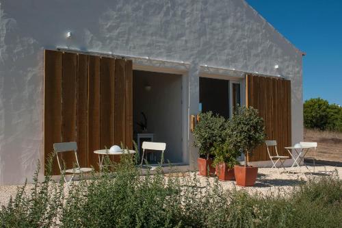 un edificio con sillas y una mesa frente a él en Alma Cheia Sunrise Studio Apartment, en Odeceixe