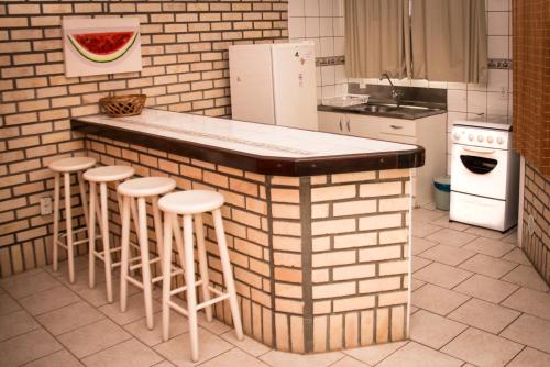 Una cocina con una encimera con taburetes y un refrigerador. en Pousada Mare Mansa, en Bombinhas