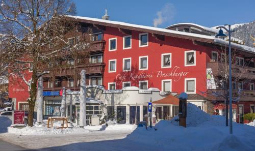 a red building on a street with snow on the ground at Hotel Garni & Appartements Ilgerhof in Walchsee