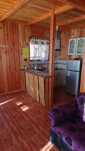 a kitchen in a log cabin with a stove and a refrigerator at Coñaripe Kuyen Mapu Cabañas in Coñaripe