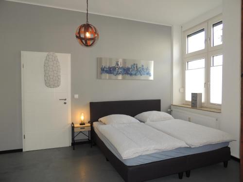 a white bedroom with a bed and a lamp at Zentrales Apartment in Gelsenkirchen in Gelsenkirchen