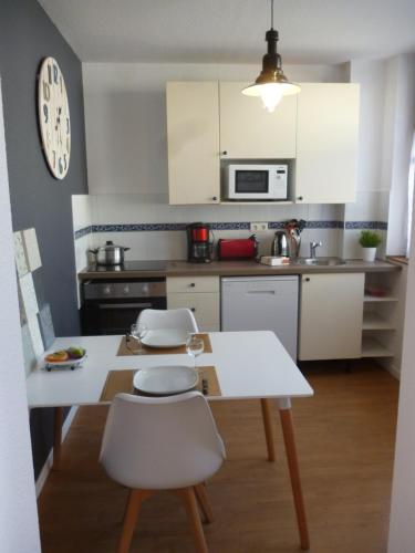 - une cuisine avec une table blanche et des chaises blanches dans l'établissement 4 Clarence app avec parking Hyper centre Thonon, à Thonon-les-Bains