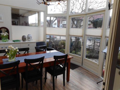 a dining room with a table and chairs and windows at B&B De Duinhoek in Beverwijk