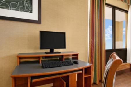 a desk with a computer monitor and a keyboard at Super 8 by Wyndham Oxford in Oxford