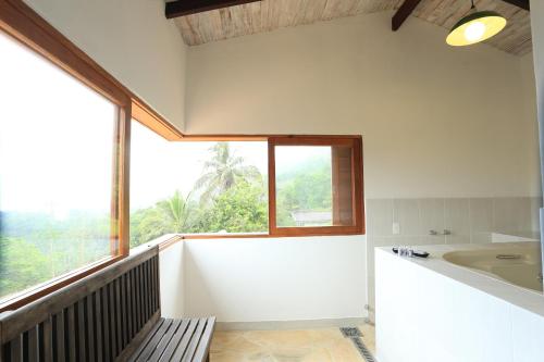 a bathroom with a bench and a large window at Chalés Mariolinha in Ilhabela