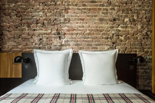 two pillows on a bed in front of a brick wall at Hôtel Louvre-Lens - Esprit de France in Lens