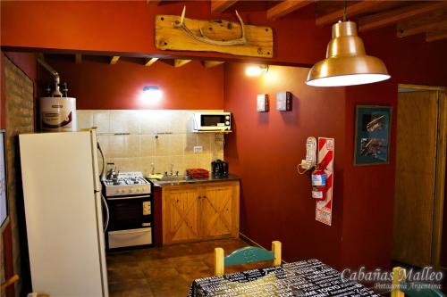eine Küche mit roten Wänden und einem weißen Kühlschrank in der Unterkunft Cabañas Malleo in Junín de los Andes