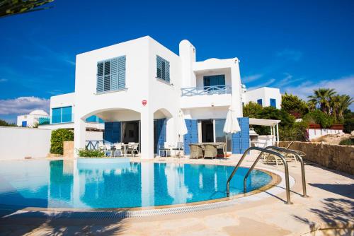 a white house with a swimming pool in front of it at Luxury Seaview Apollo Beach Villa in Paphos