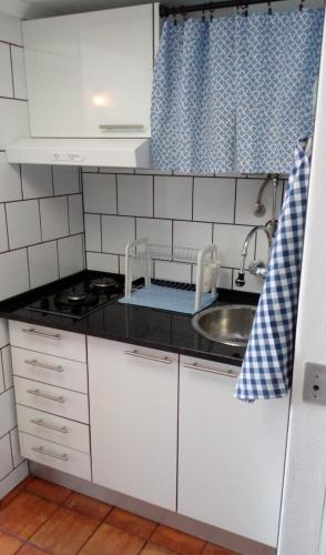 a small kitchen with white cabinets and a sink at Casa do Espadarte in Sesimbra