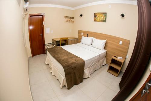 a hotel room with a bed and a table at Hotel Máximos in Itapetininga