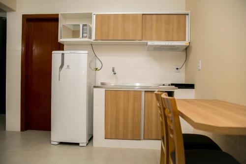 a small kitchen with a refrigerator and a table at Hotel Máximos in Itapetininga