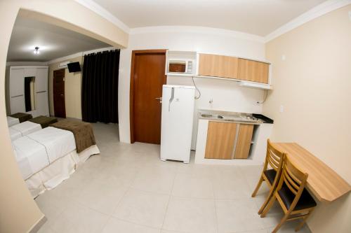 a small kitchen with a refrigerator and a table at Hotel Máximos in Itapetininga