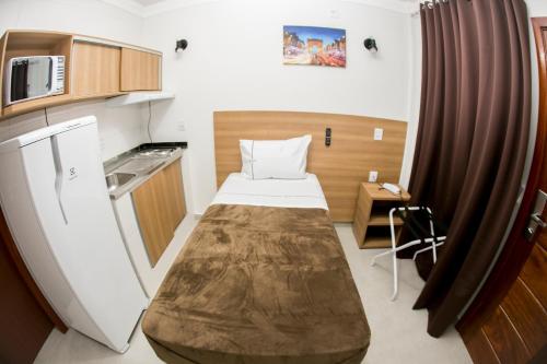 a small room with a bed and a kitchen at Hotel Máximos in Itapetininga