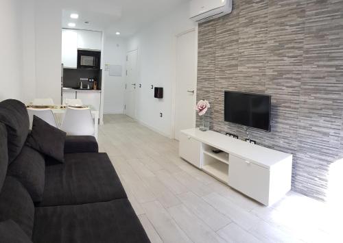 a living room with a couch and a tv on a brick wall at Málaga Alcolea in Málaga