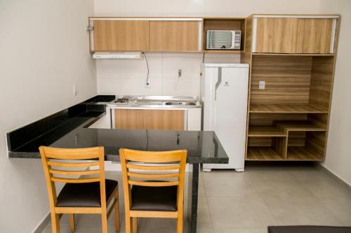 a kitchen with a table and two chairs and a refrigerator at Hotel Máximos in Itapetininga