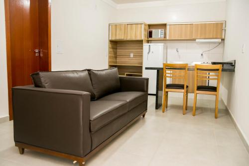 a living room with a couch and a kitchen at Hotel Máximos in Itapetininga