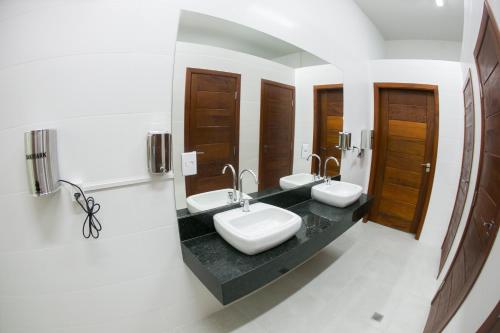 a bathroom with two sinks and two mirrors at Hotel Máximos in Itapetininga