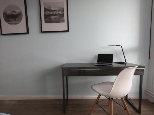 - un bureau noir avec un ordinateur portable et une chaise blanche dans l'établissement Cozy Appartement Gare Pompidou, à Metz