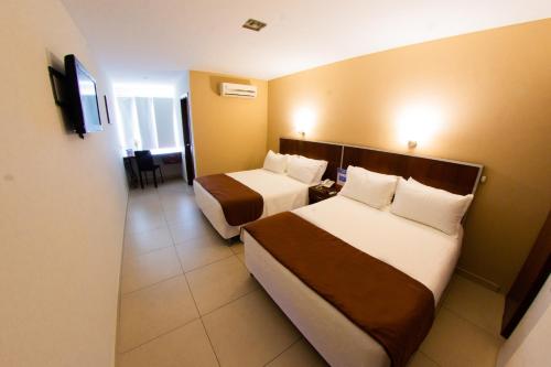 a hotel room with two beds and a television at Torre Hotel Ejecutivo in Santa Cruz de la Sierra
