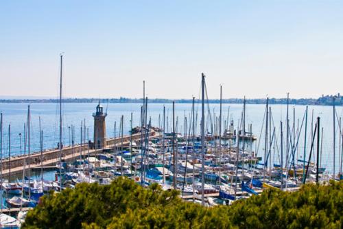 a group of boats docked at a dock with a lighthouse at Hotel Vittorio in Desenzano del Garda