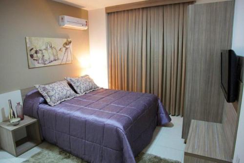 1 dormitorio con cama morada y TV de pantalla plana en Encontro das Águas, en Caldas Novas