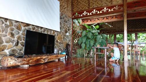a man is standing in a living room with a tv at Camiguin Volcano Houses-Panoramic House in Mambajao