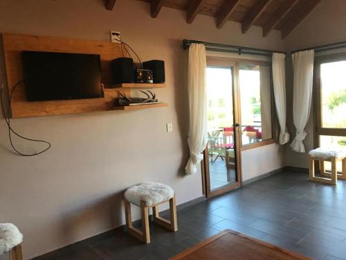 uma sala de estar com dois bancos e uma televisão na parede em Departamento Cipres Villa Huapi Bariloche em San Carlos de Bariloche