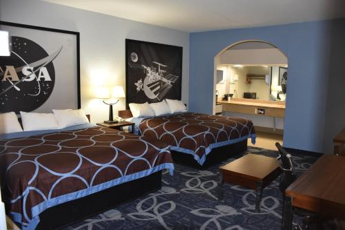 a hotel room with two beds and a mirror at Super 8 by Wyndham Houston Hobby Airport South in Houston