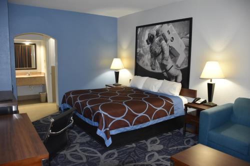 a hotel room with a bed and a blue wall at Super 8 by Wyndham Houston Hobby Airport South in Houston