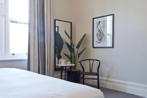 um quarto com uma cama e duas cadeiras e uma planta em Villa Maria Barossa Luxury Guesthouse em Tanunda