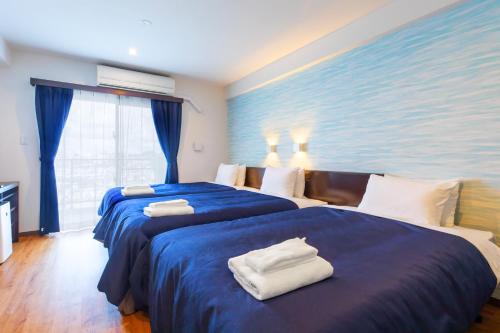 a hotel room with two beds with towels on them at Cococious Monpa in Chatan