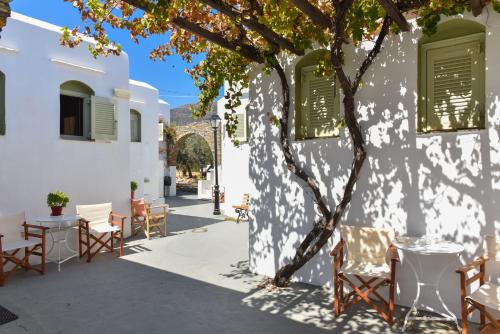 a patio with chairs and a tree in front of a building at Giannakas Studios in Platis Yialos Sifnos
