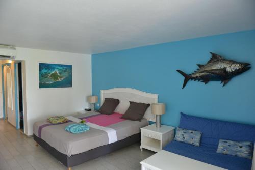 a bedroom with a bed and a fish on the wall at studio "BLEU TURQUOISE" in Le Gosier